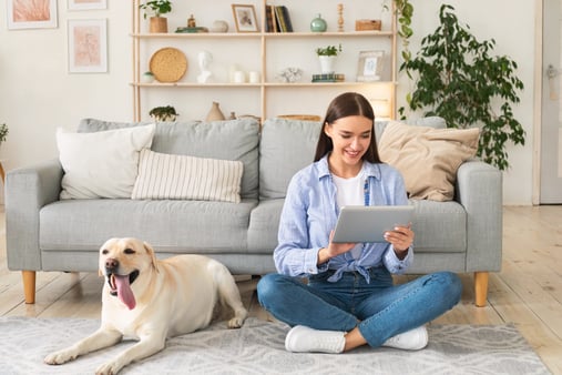 young-woman-at-home-with-a-tablet-and-dog-YBWL74L